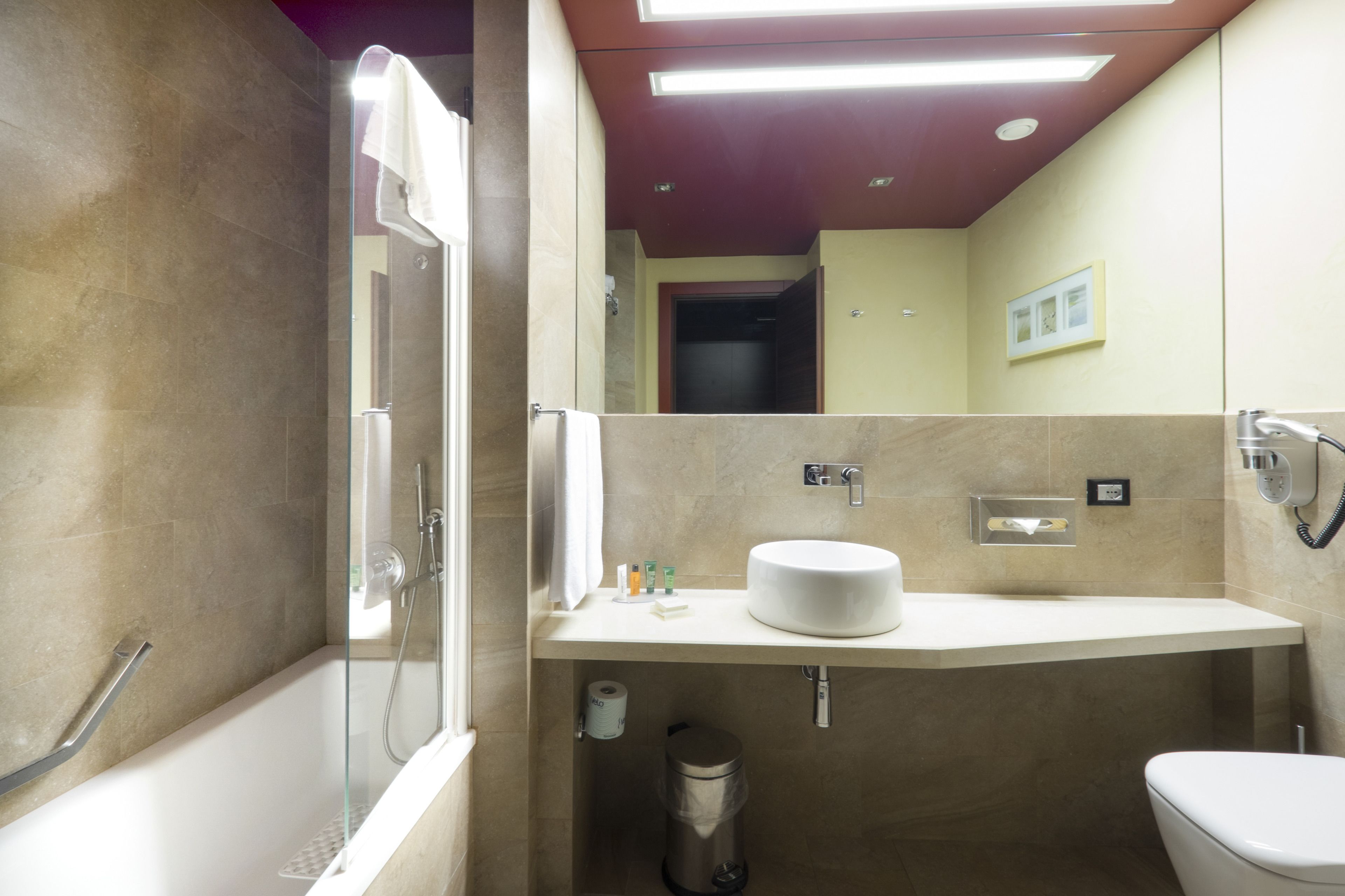 Un bany modern amb dutxa de vidre, un lavabo blanc i un vàter.