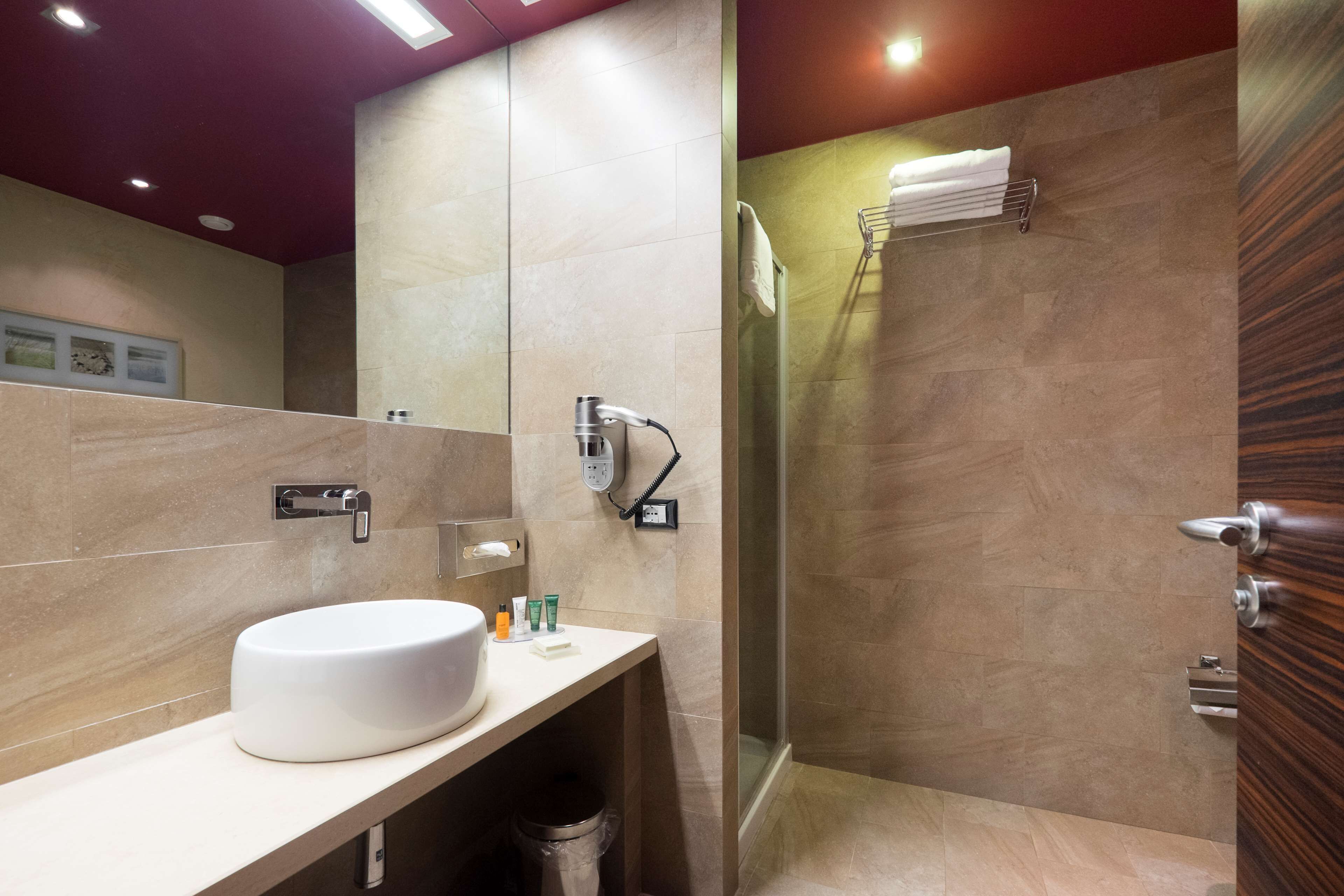 Un baño moderno con un lavamanos grande, una ducha y un perchero para toallas.