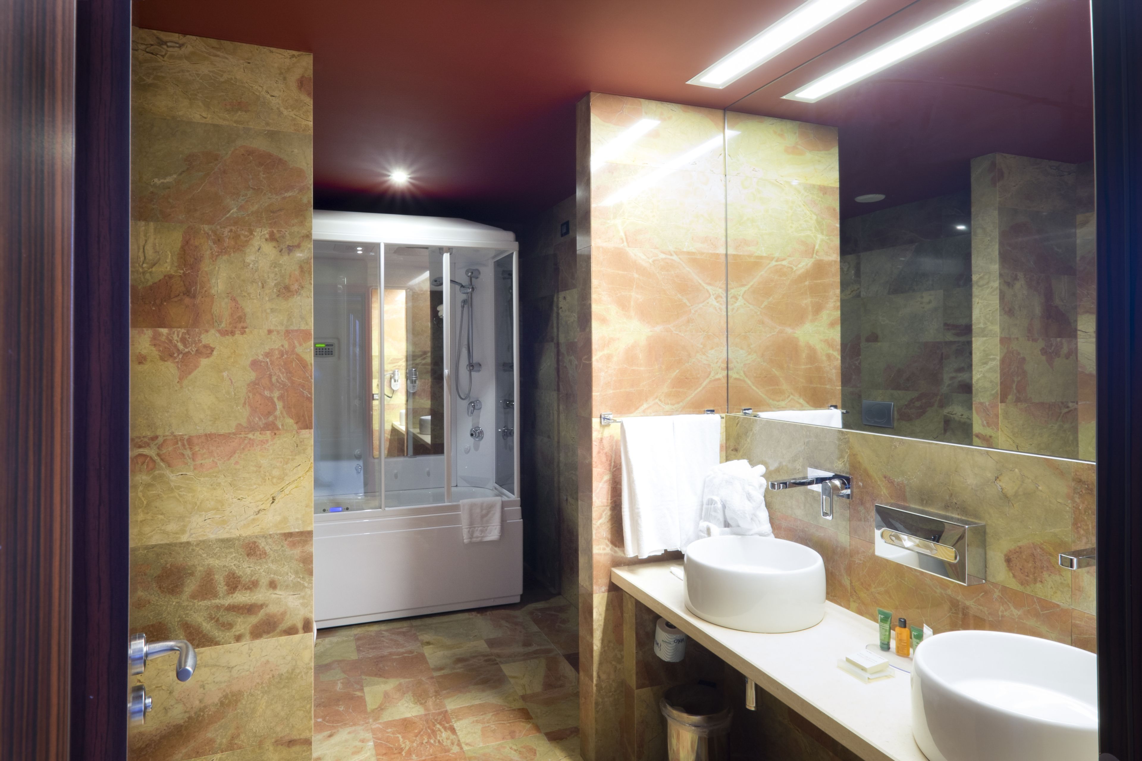 A modern bathroom with a glass-enclosed shower, a large mirror, and two sinks.