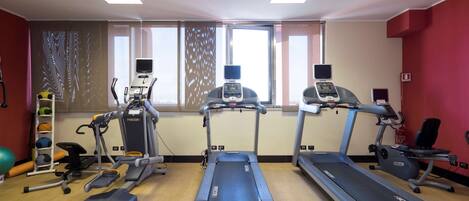 Academia com esteiras, elípticos e um banco de musculação.