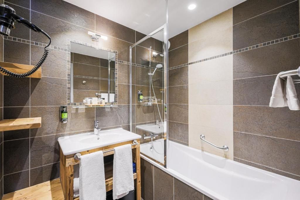 A modern bathroom with a glass-enclosed shower, a vanity with a mirror, and a bathtub.