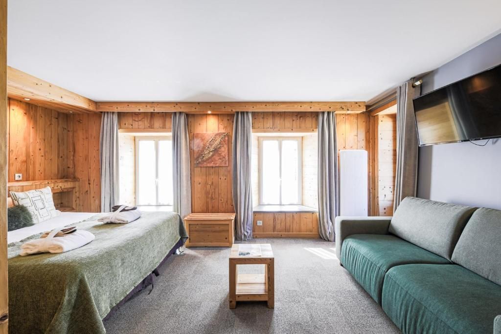 A room with a bed, a sofa, a small table, and a television.