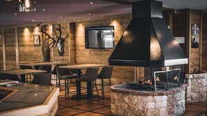 Een restaurant met een stenen openhaard, houten wanden en een aan de muur bevestigde televisie.