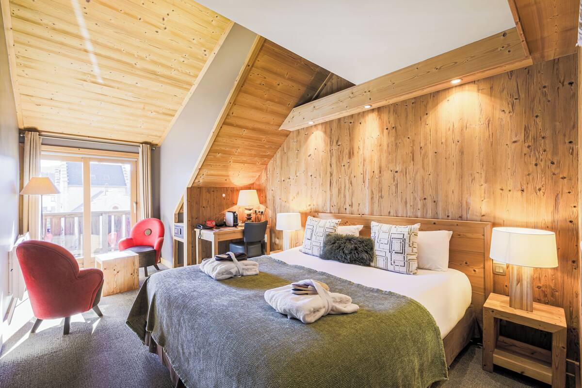 Une pièce confortable avec un lit, un bureau, une chaise et une fenêtre.