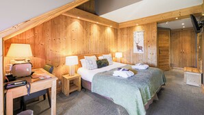 Een kamer met houten lambrisering, met een bed, bureau en stoel, voorzien van lampen en een telefoon.