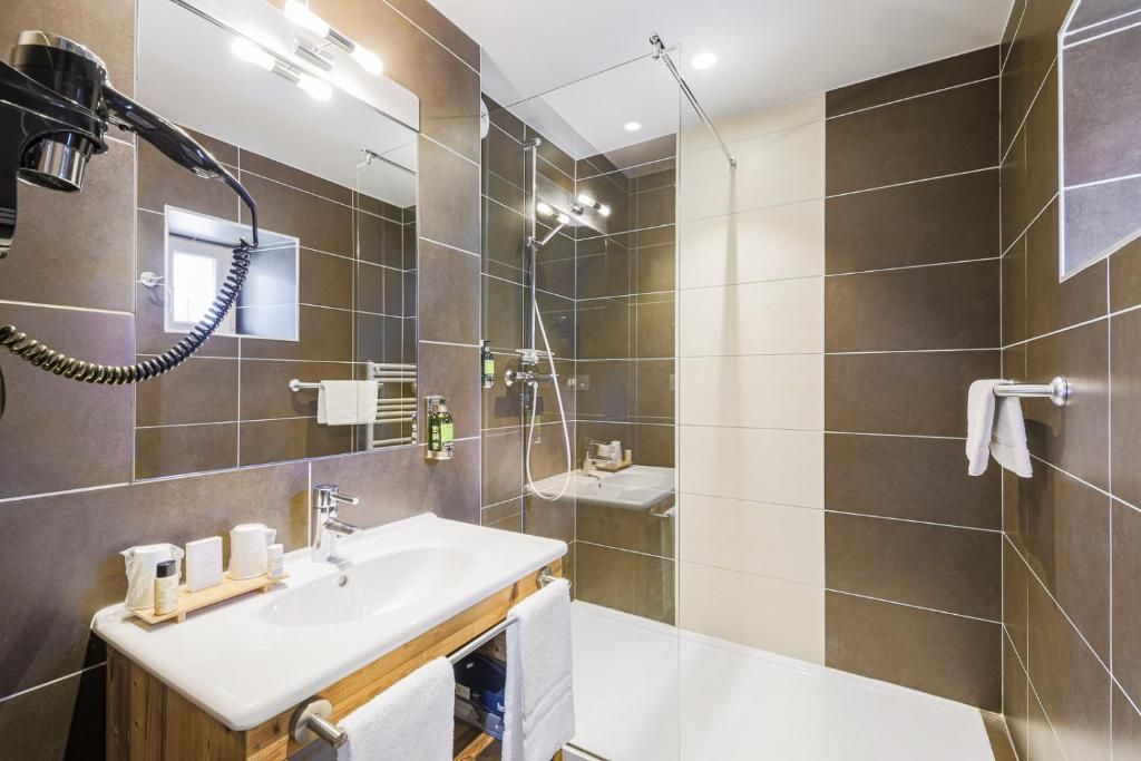 A modern bathroom with a large mirror, a sink, a shower, and a towel rack.