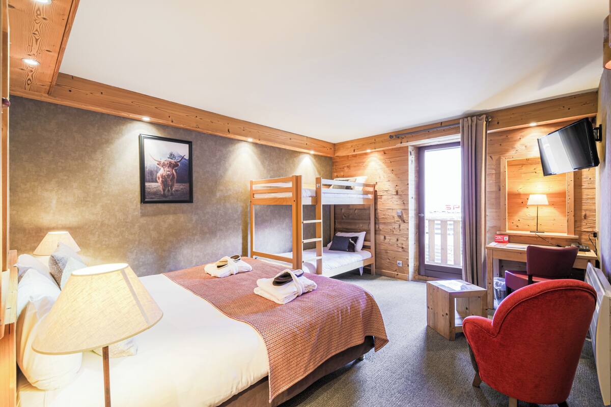 Une chambre avec un lit superposé, un bureau avec une chaise, une télévision et une lampe.