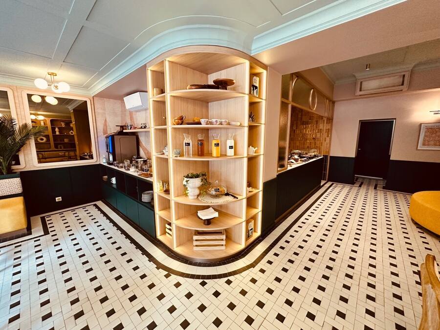 Een hotel lobby met een centraal houten wandrek waarop diverse items staan, een vloer met patroon en een modern plafondontwerp.