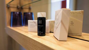 Une étagère contenant divers produits, notamment une bouteille noire portant l’étiquette « après-shampoing RITUALS » et des boîtes blanches avec du texte.