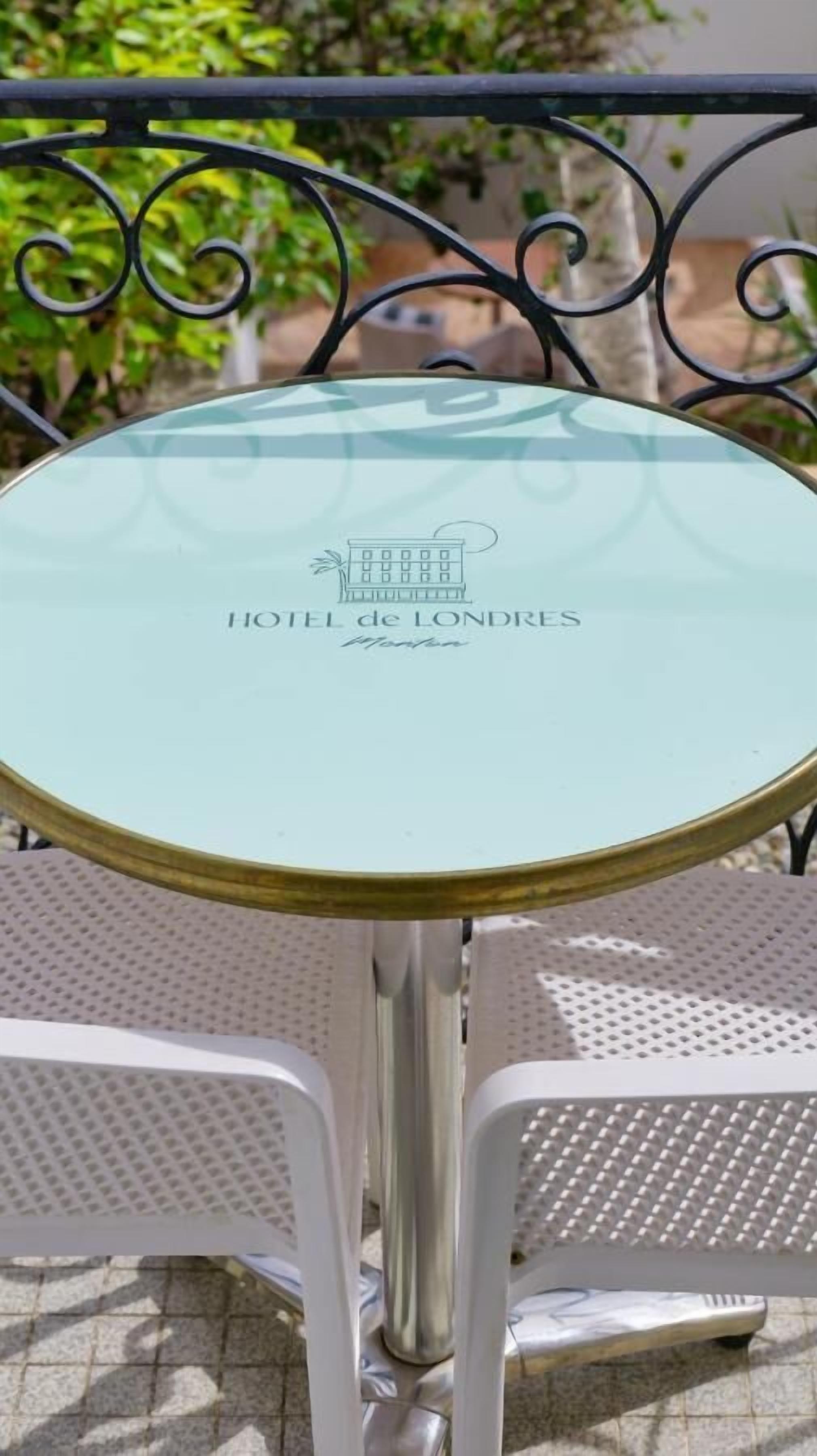 A round glass table with a metal frame, labeled "HOTEL de LONDRES."