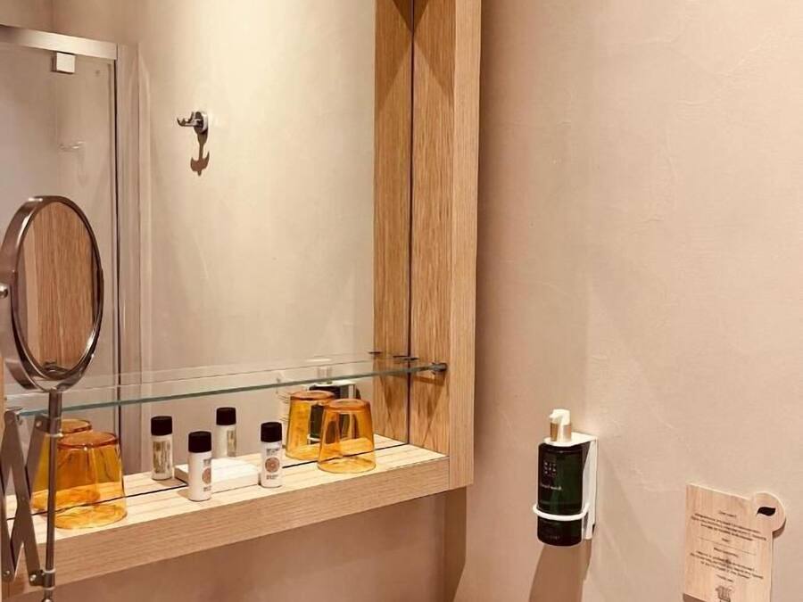 Un baño con tocador de madera, un espejo, un lavamanos y dispensador de jabón.