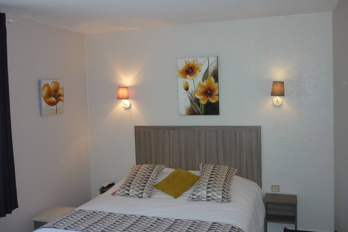 Una habitación de hotel con una cama, dos lámparas de pared y dos cuadros.