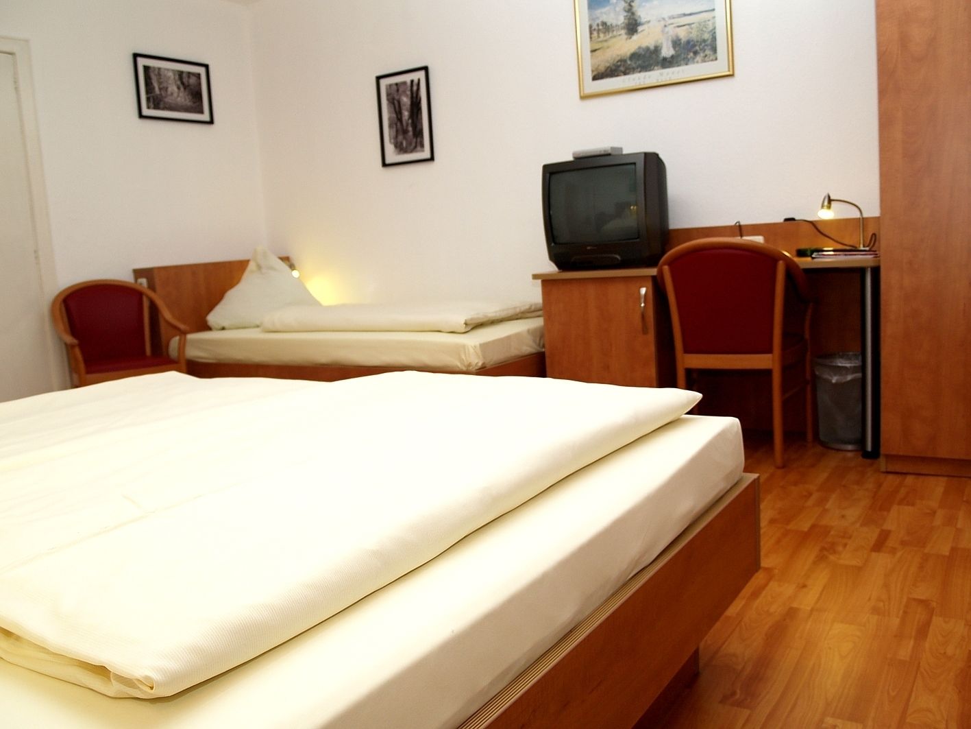 Une chambre d’hôtel équipée d’un lit, d’un bureau, d’une chaise, d’une télévision et d’une poubelle.