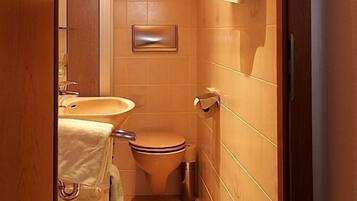 Un bagno compatto con soffitto in legno, un water, un lavabo e uno specchio.
