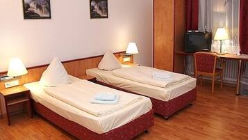 Ein Hotelzimmer mit zwei Betten, einem Schreibtisch, einem Stuhl und einem Fernseher.