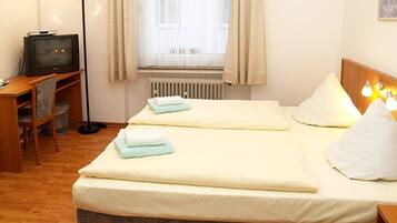 Une chambre d’hôtel avec deux lits, un bureau avec une télévision et un radiateur.