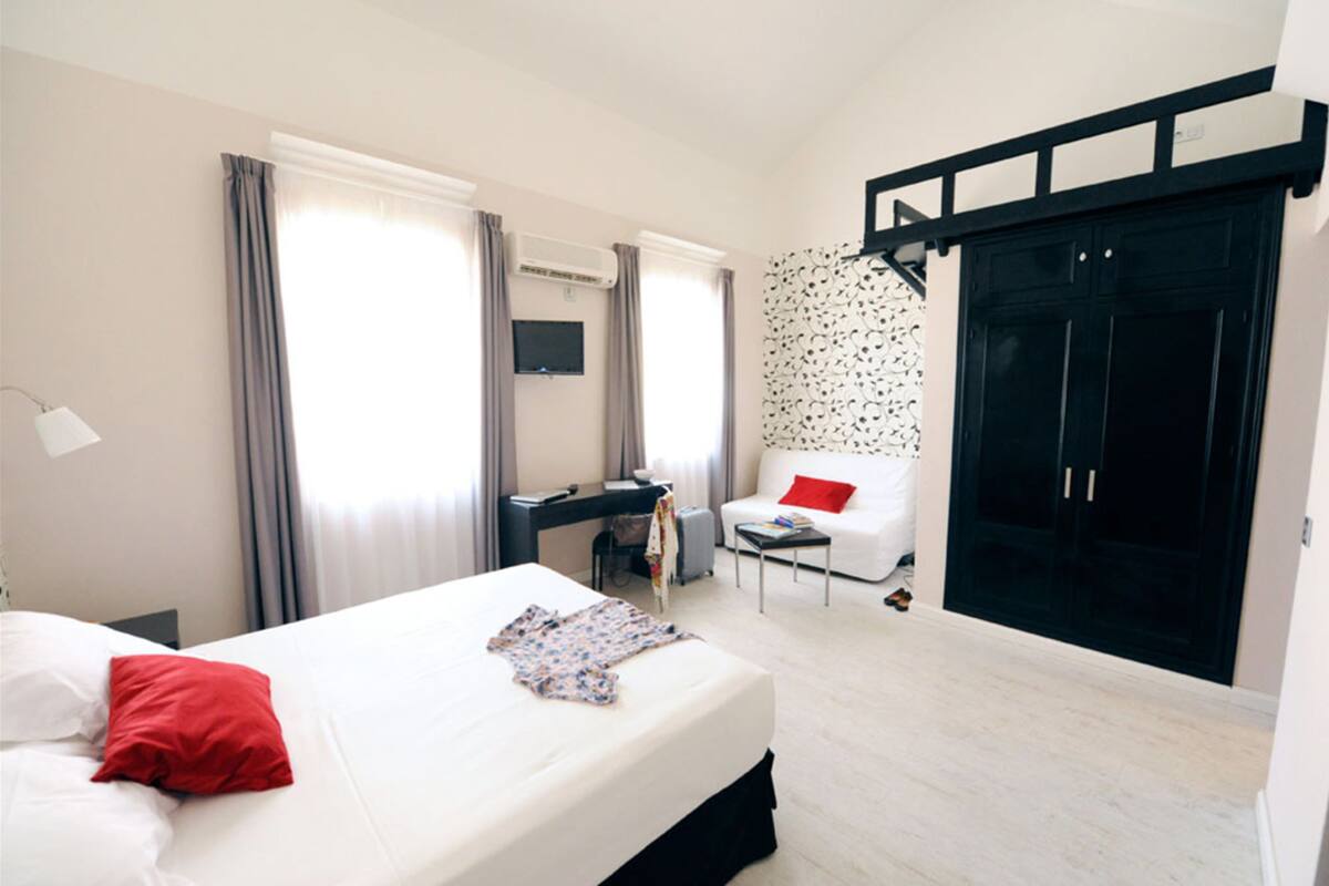 A modern hotel room with a bed, desk, and wardrobe.