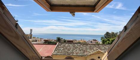 A skylight with a view of the sea and buildings below.