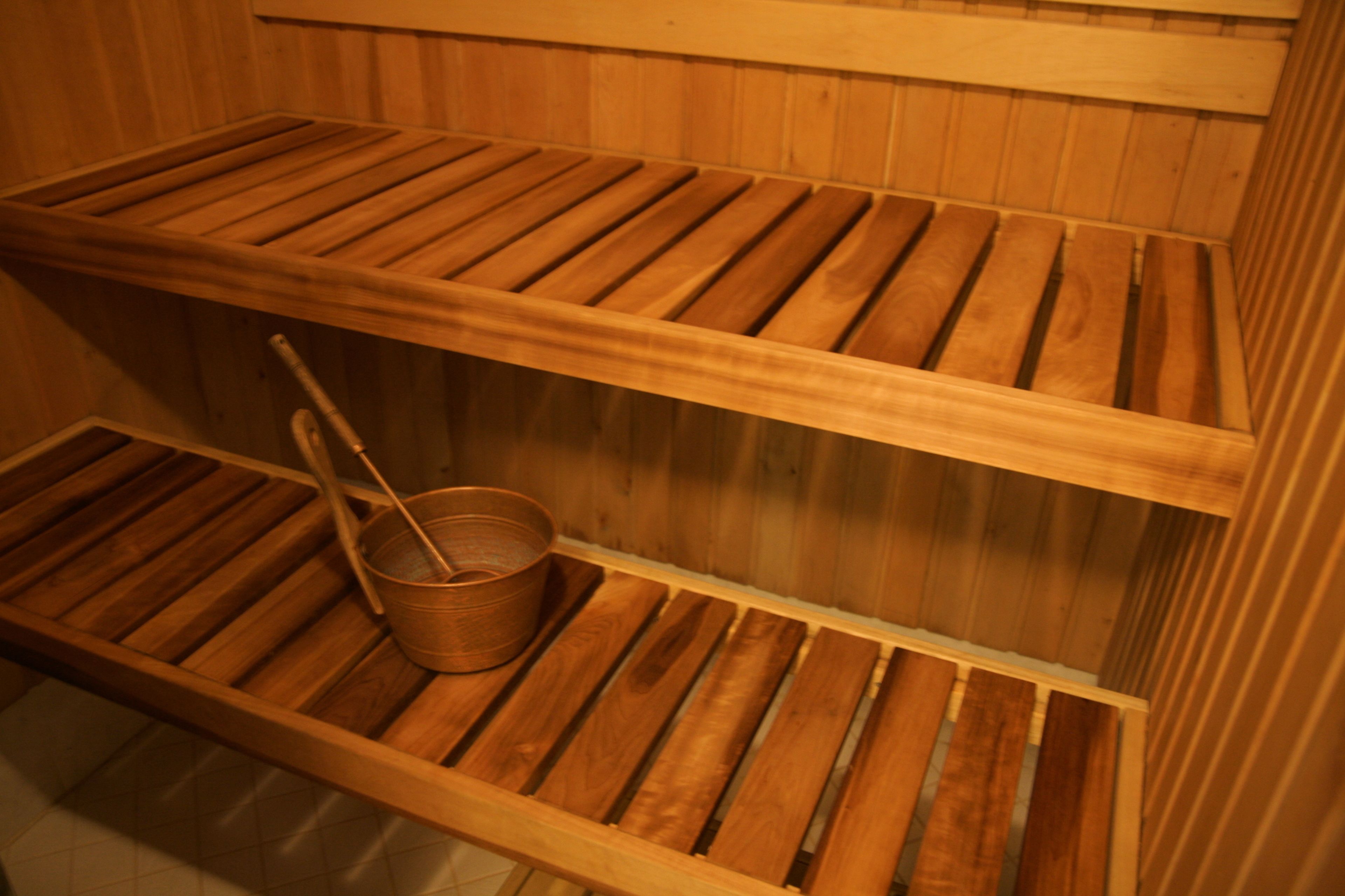Una sauna de madera con dos bancos y un cubo.
