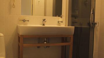 A bathroom with a sink, mirror, and shower.