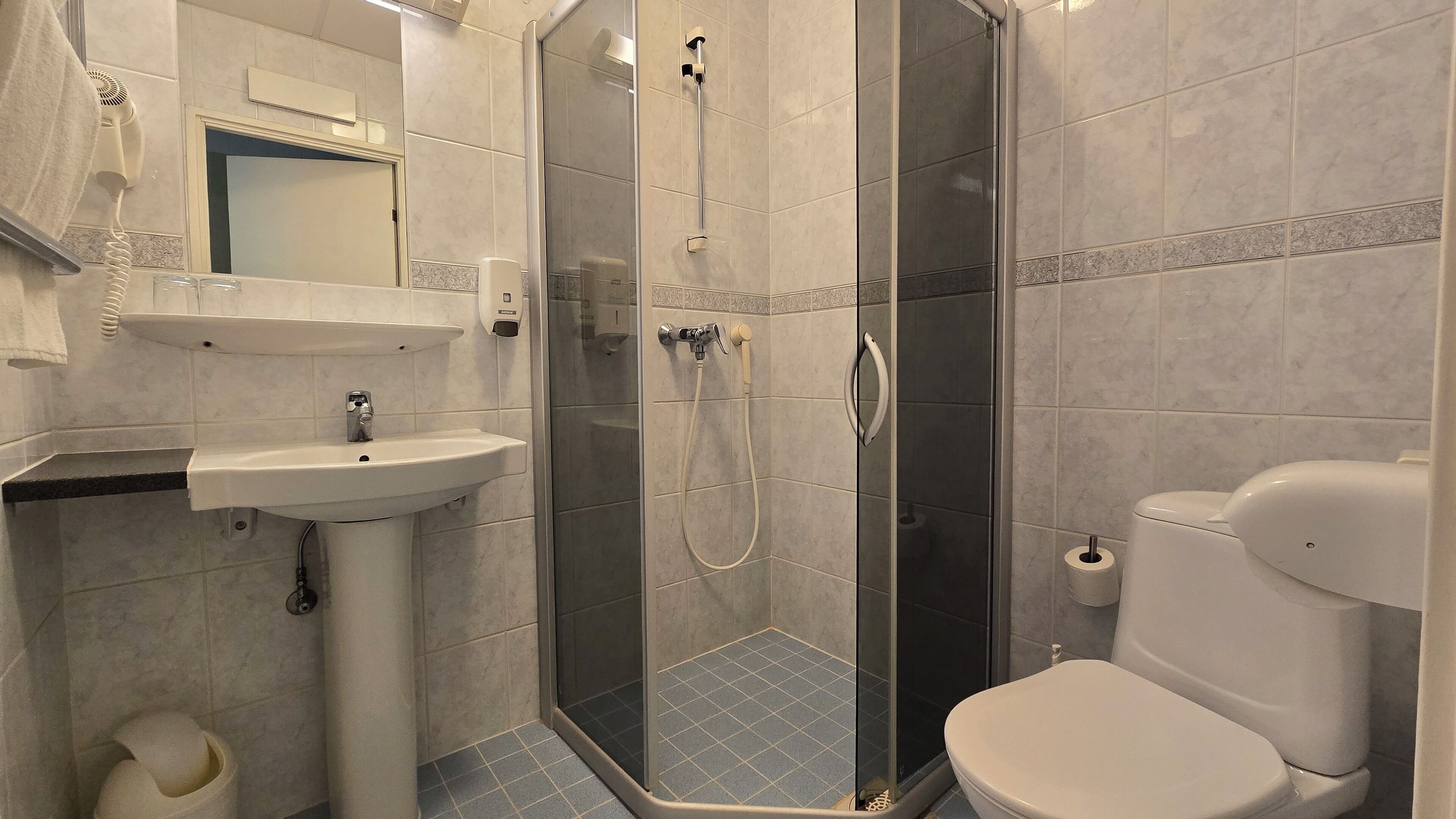 Un baño con lavabo, inodoro y ducha con mampara de vidrio.
