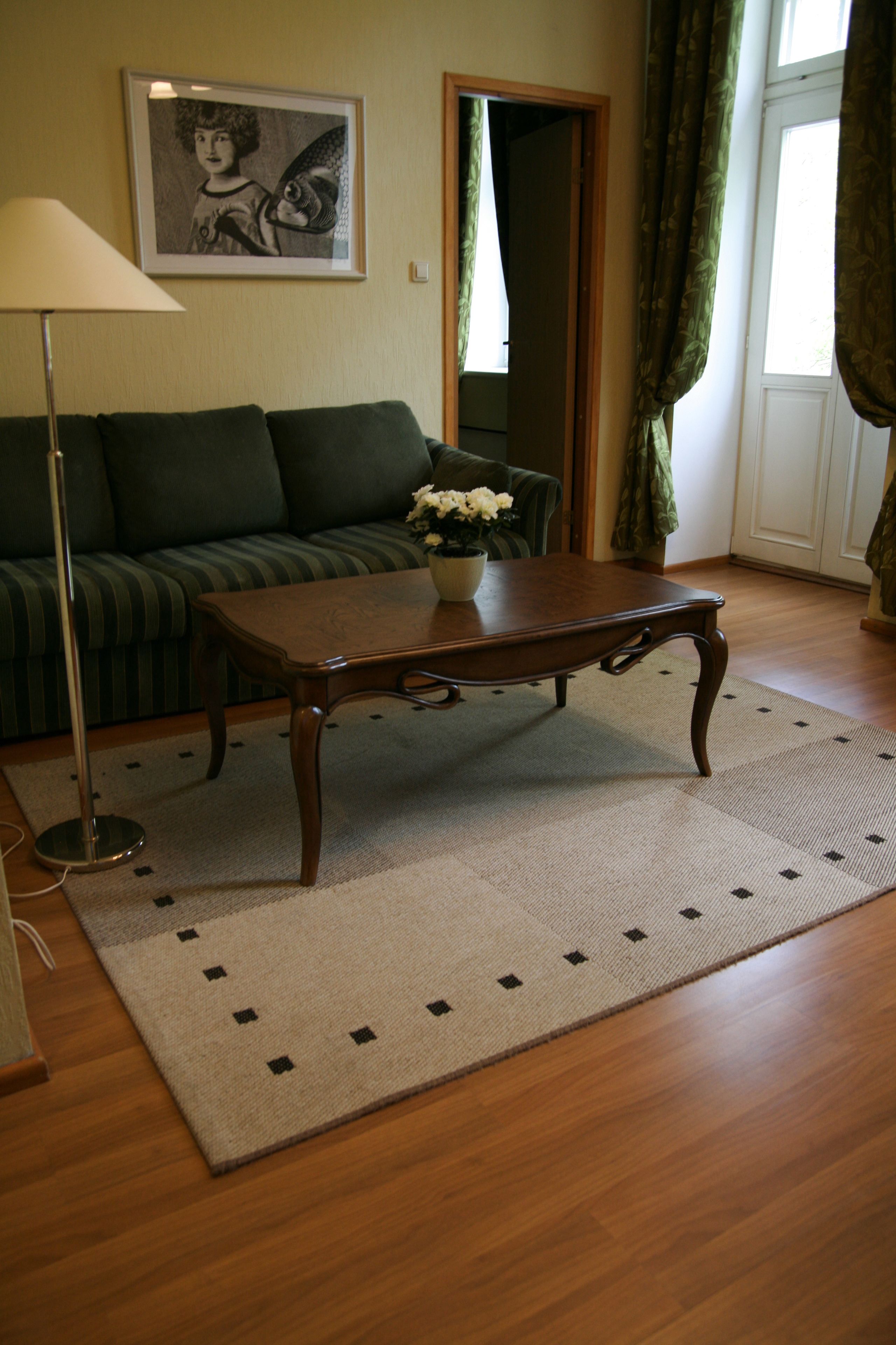 A living room with a wooden coffee table, a sofa, a lamp, and a framed picture on the wall.