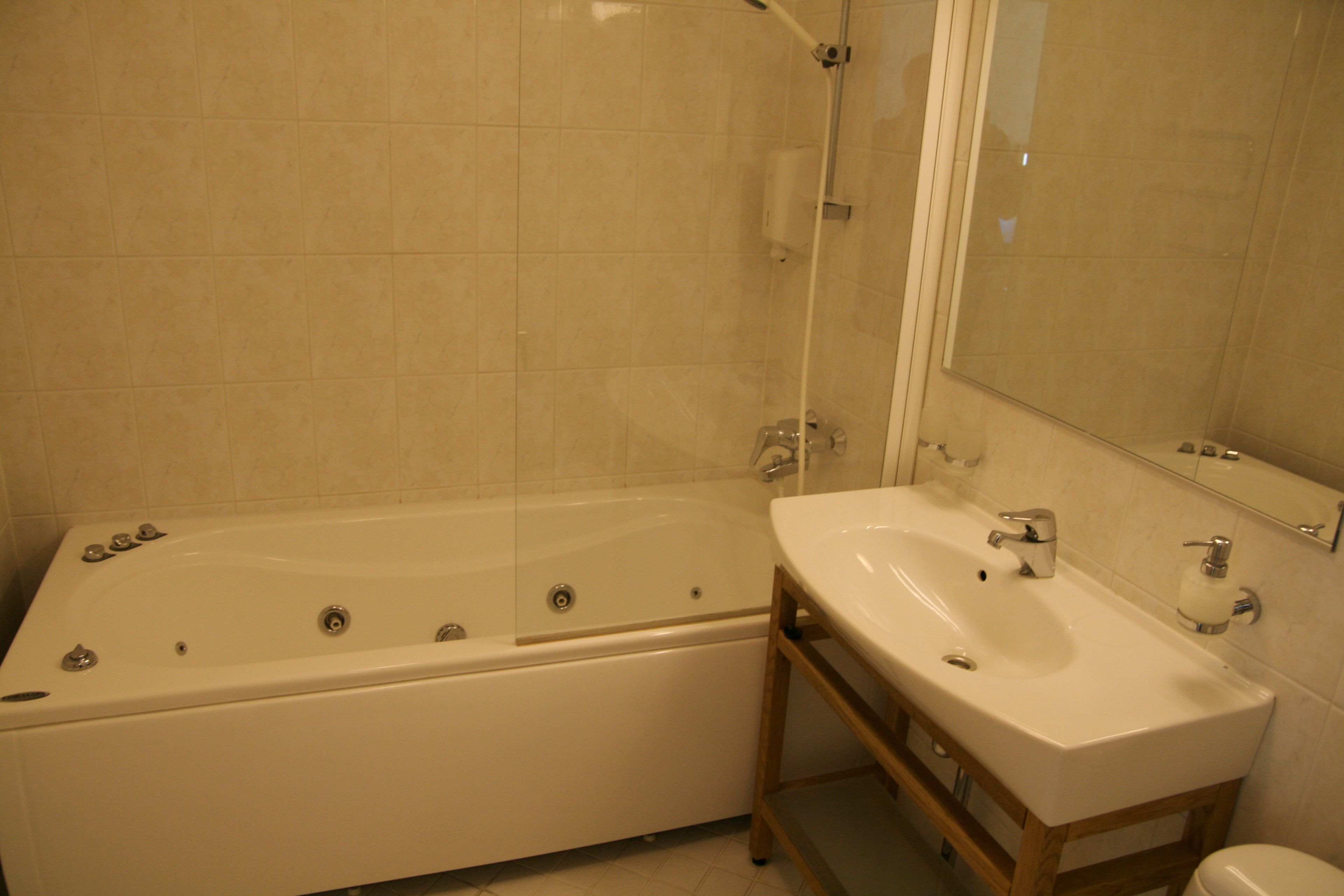 Une salle de bain avec une baignoire, un lavabo et un miroir.