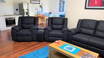 A living room with a black leather sofa, a wooden coffee table, and a blue rug.