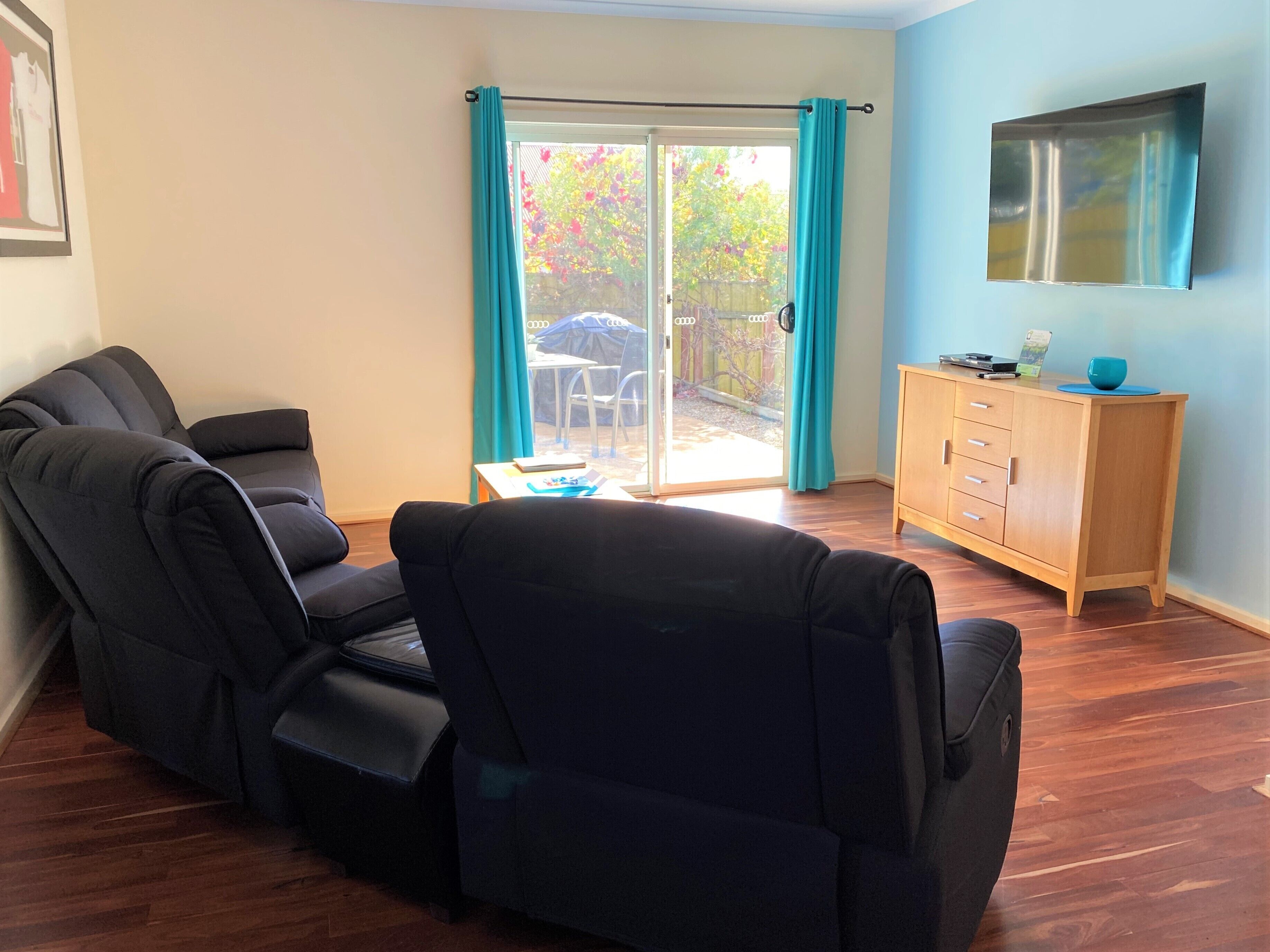 A living room with a sofa, a wooden cabinet, and a sliding glass door leading to an outdoor area.