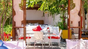 Un espace extérieur aménagé avec une pergola en bois, des chaises blanches et une table.