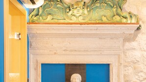 Une pièce avec une porte bleue, un mur en pierre blanche et un plafond décoratif.