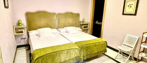 Un letto matrimoniale con copriletto verde, due comodini, una sedia e una porta che conduce al bagno.