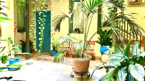 A courtyard with potted plants, a tiled floor, and a door leading to another room. - Hotel Conde de Cárdenas (Córdoba)