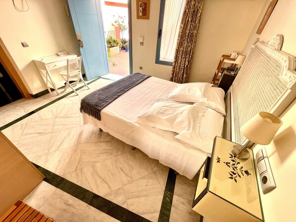 Habitación de hotel con cama, escritorio, lámpara y vista al exterior.