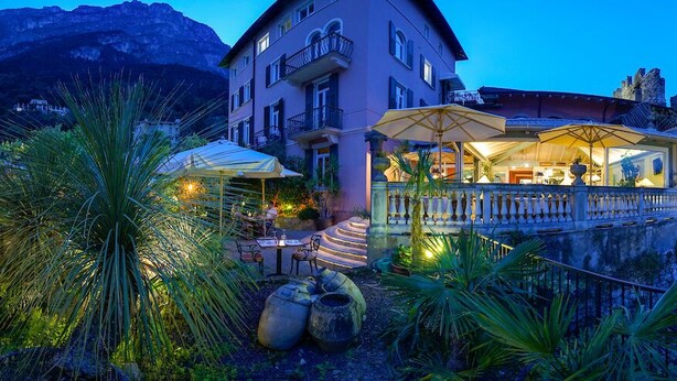 A hotel with outdoor seating, a balcony, and a view of a mountain.
