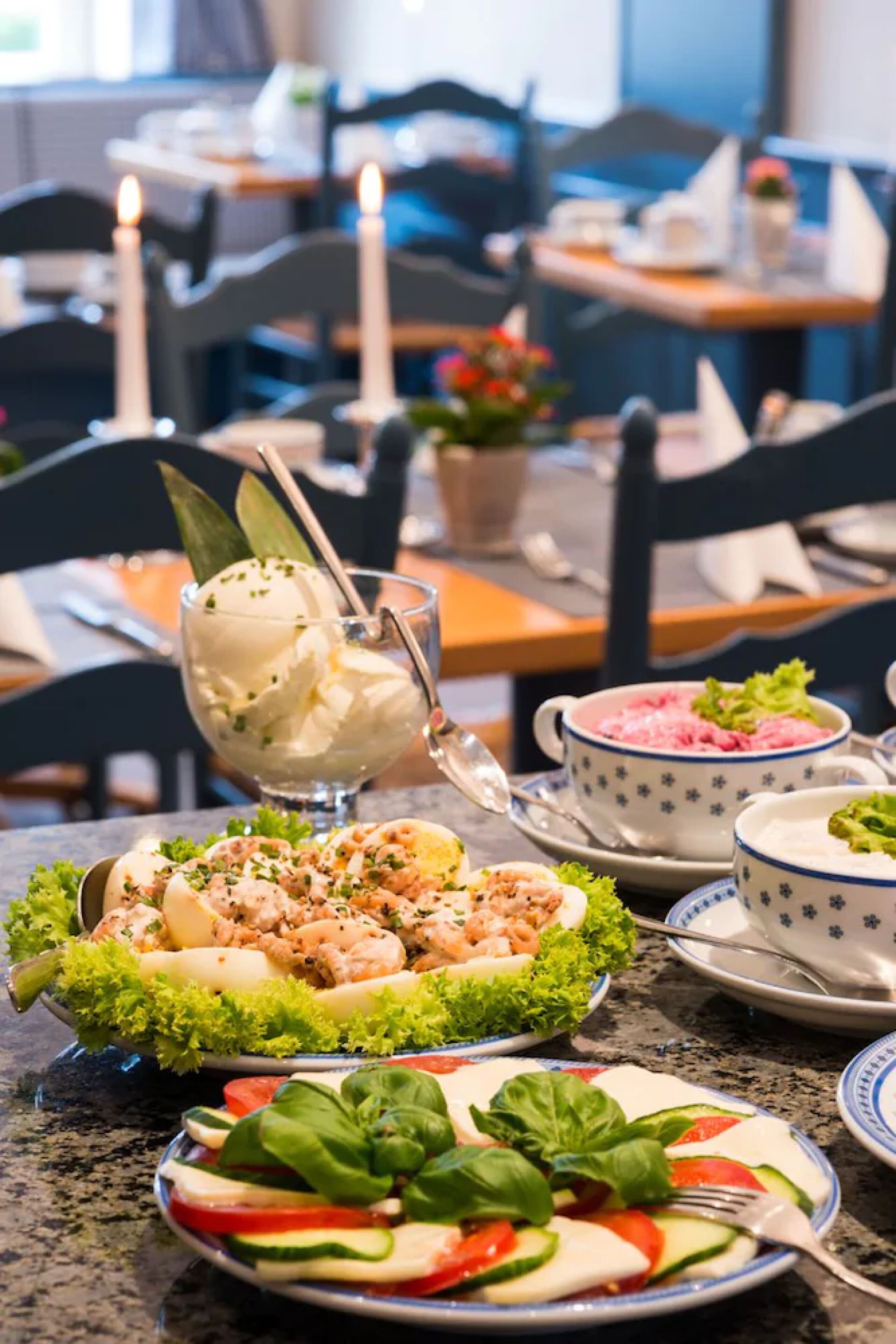 Een eettafel met diverse gerechten, waaronder een soepkom, een ijskom, een bord met garnalen en een salade.