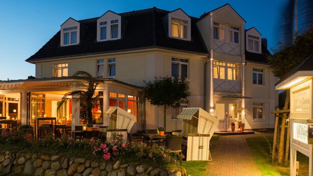 A large, two-story building with a well-lit entrance and a covered outdoor seating area.