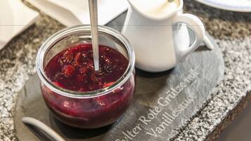 Et glas rødt marmelade med en ske, placeret på en skifer serveringsbakke med tekst.