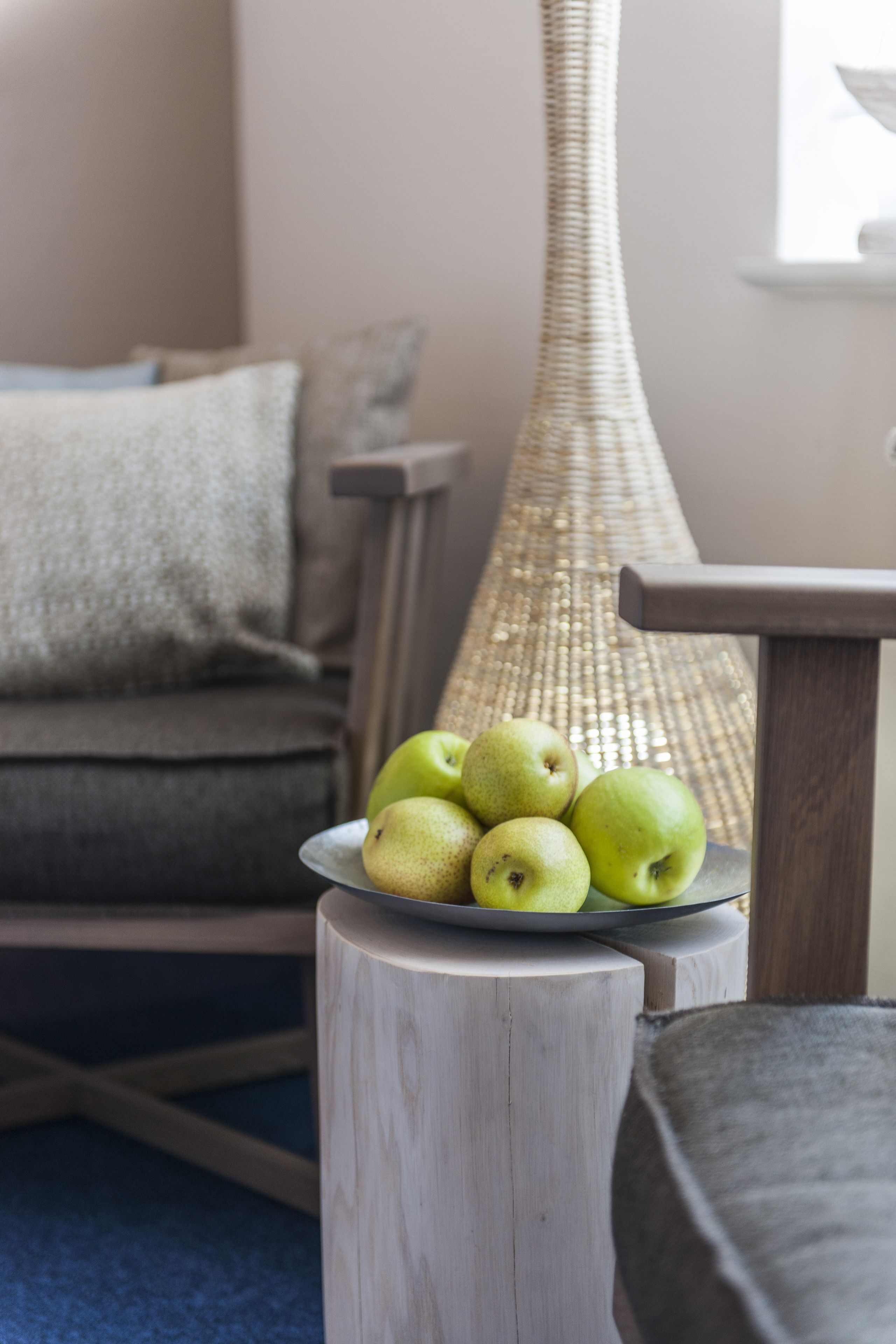 Un tabouret en bois sur lequel est posée une assiette de pommes et de poires vertes.