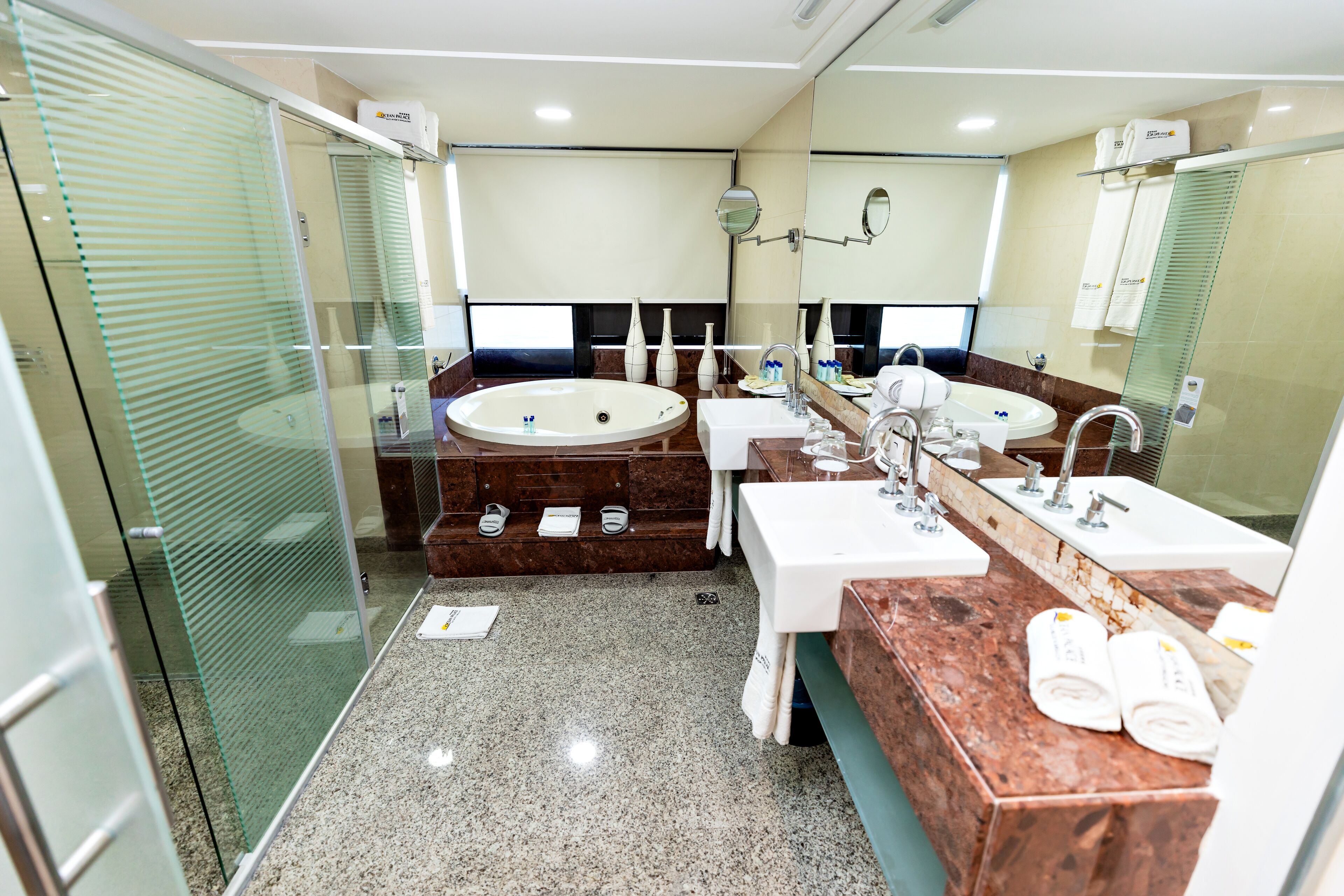 A modern bathroom with a large bathtub, two sinks, and a glass shower enclosure.