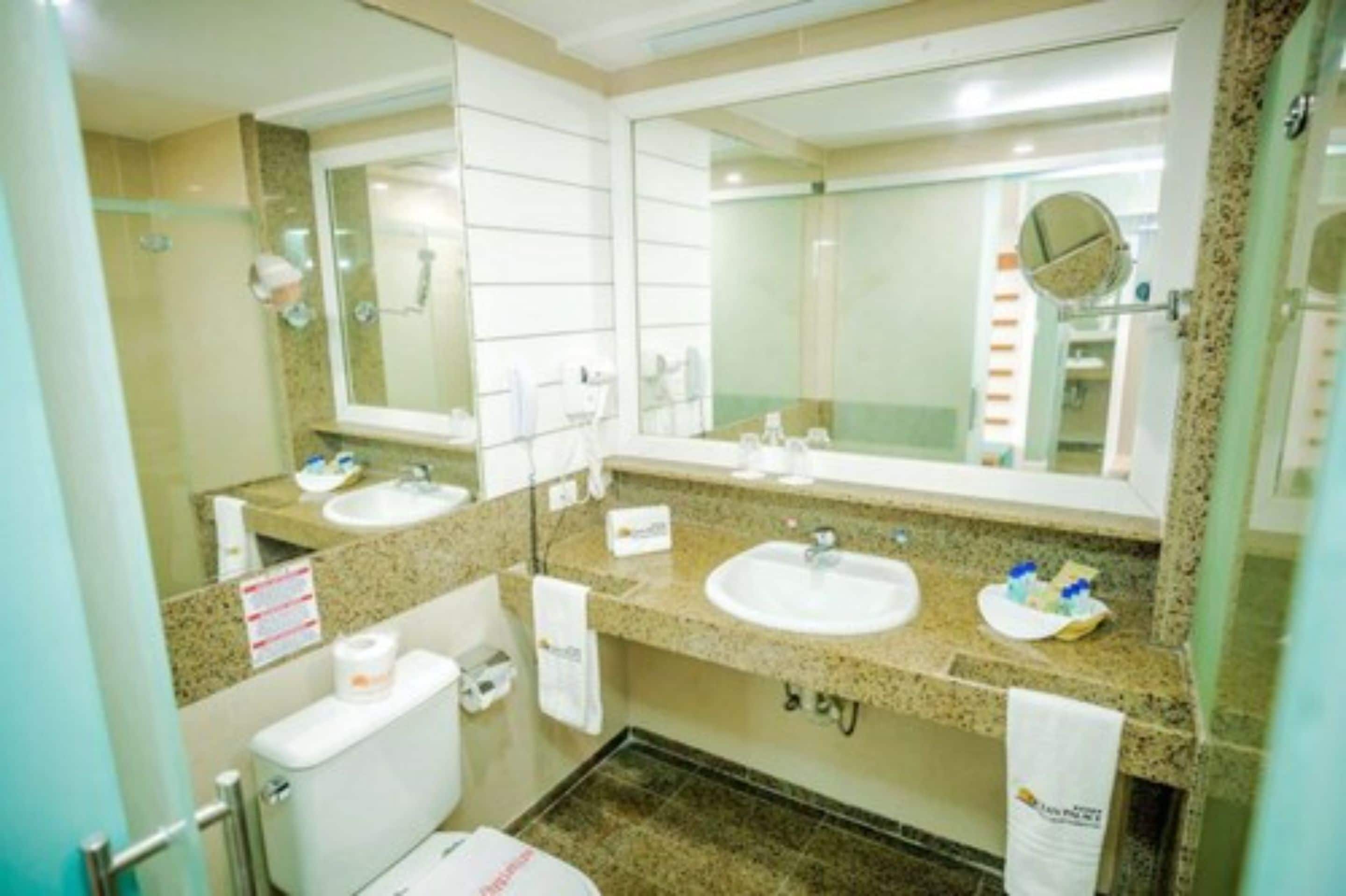 A bathroom with two sinks, a toilet, and a shower.