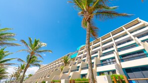 Un hotel moderno con una estructura de varios pisos, un área de estar al aire libre y palmeras.