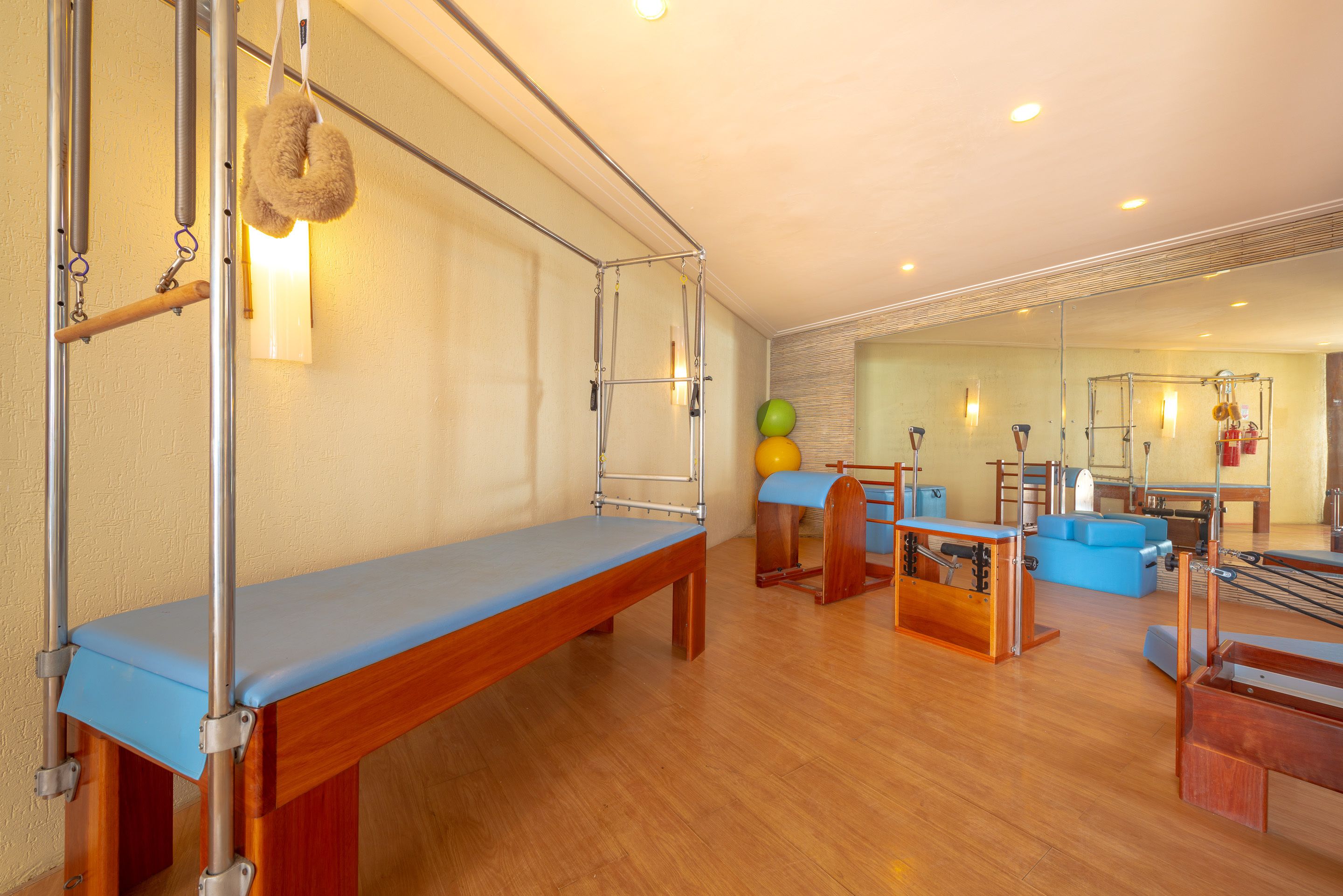 A gym with exercise equipment, a blue bench, and a mirrored wall.