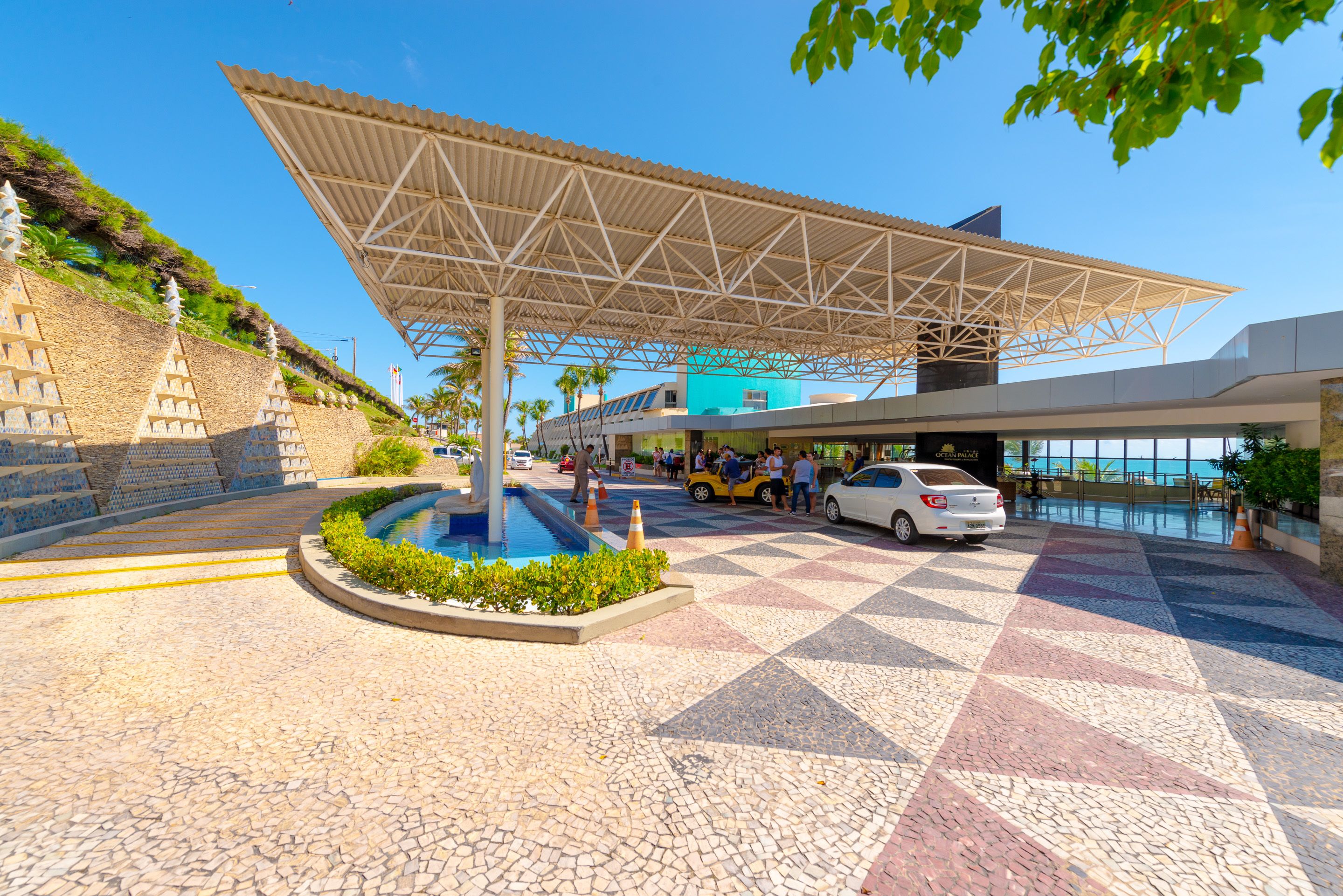 Um edifício moderno com área externa coberta, piscina e um pátio pavimentado.