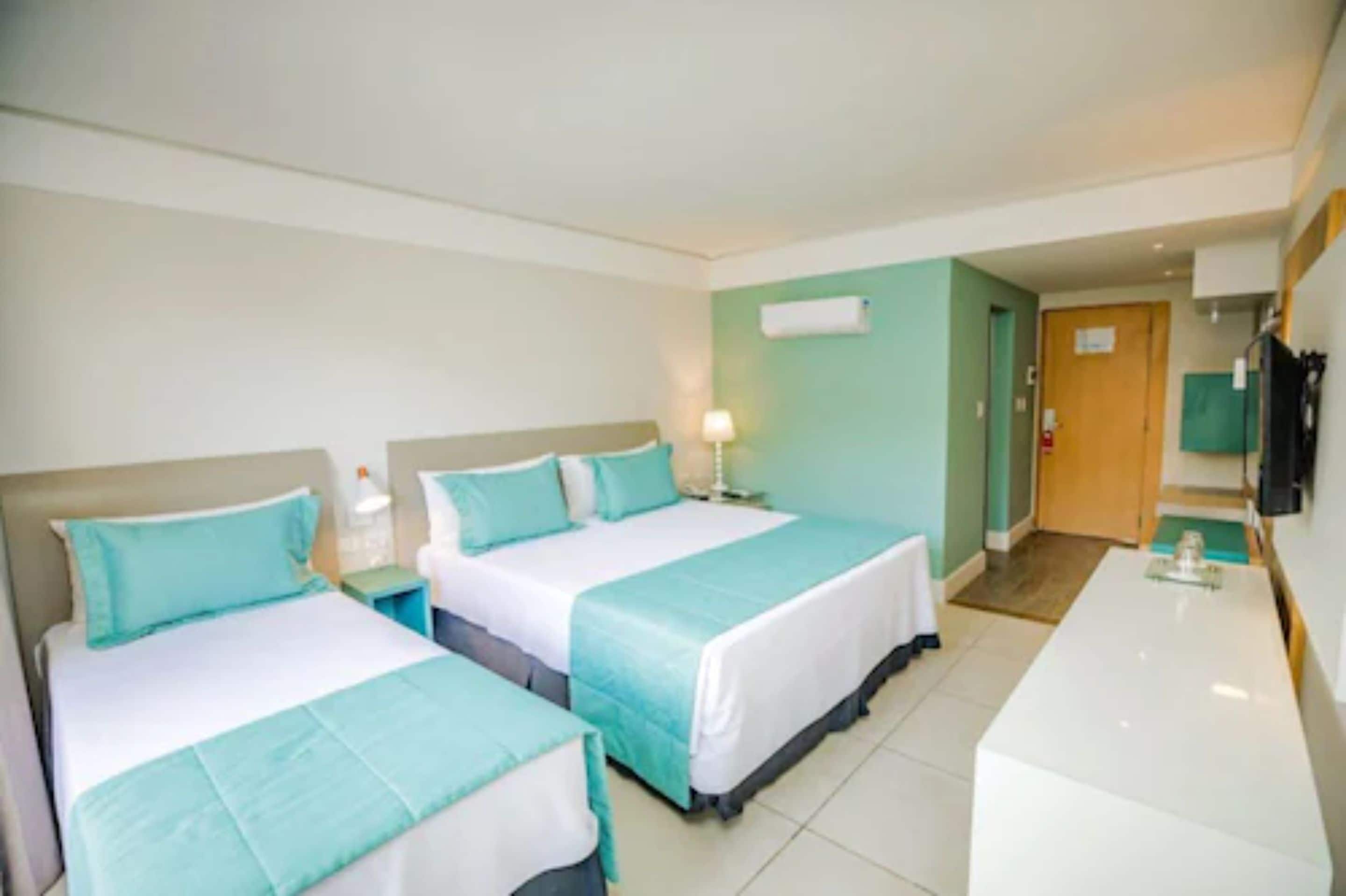 A hotel room with two beds, a desk, and a bathroom door.