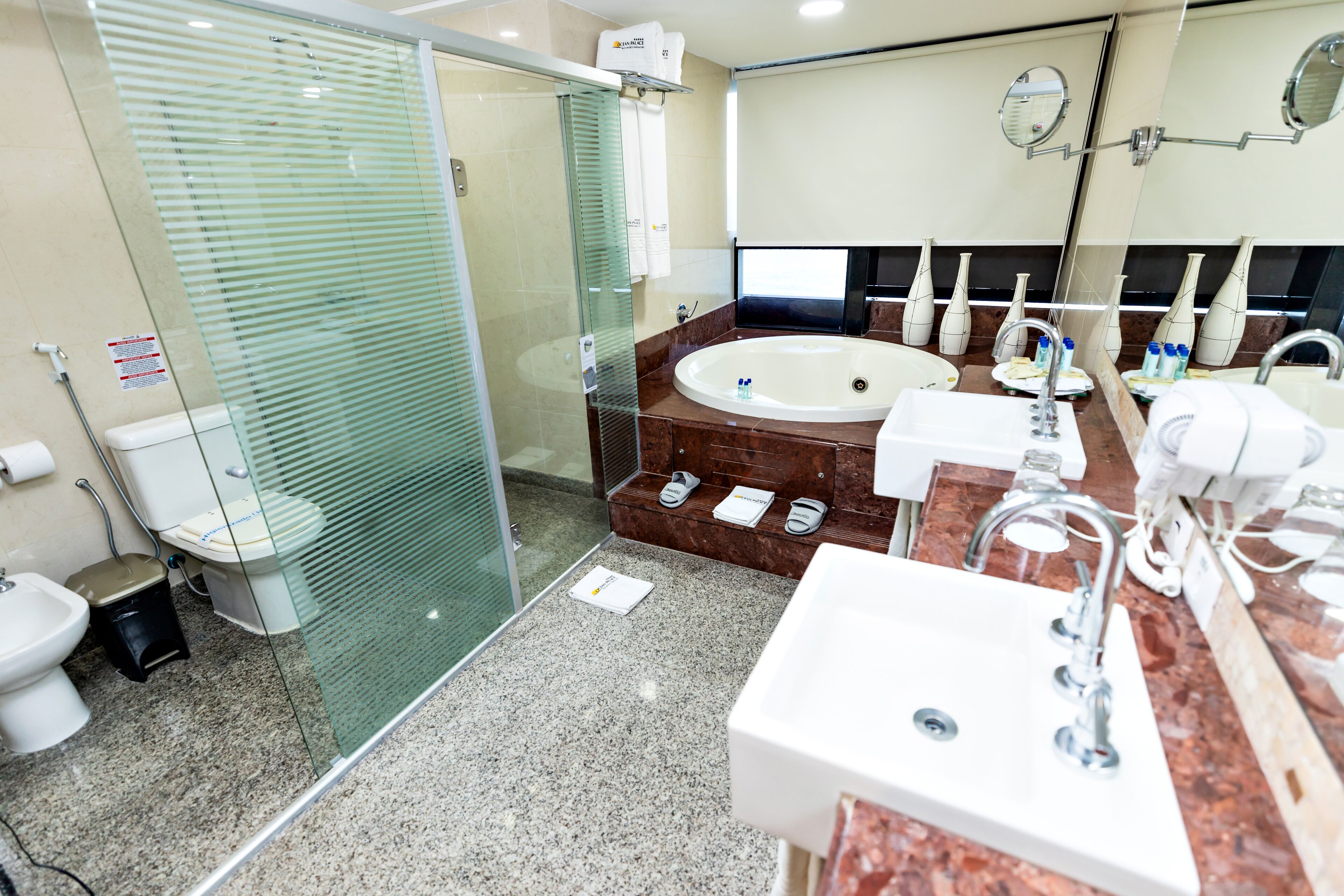 A modern bathroom with a glass-enclosed shower, a large bathtub, and a vanity with a sink and mirror.