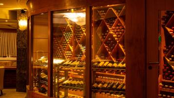 A wine cellar with glass-fronted shelves and a wooden interior.