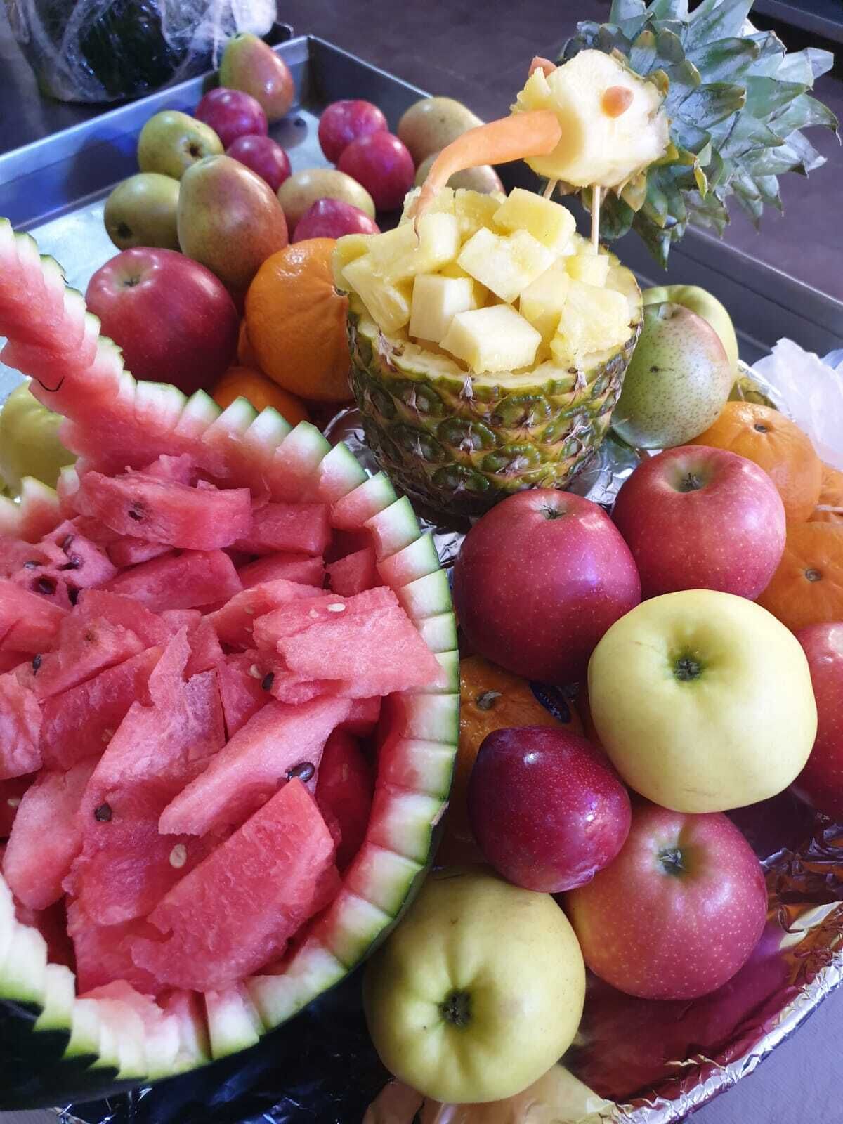 A variety of fruits including apples, oranges, and watermelon, arranged on a tray.