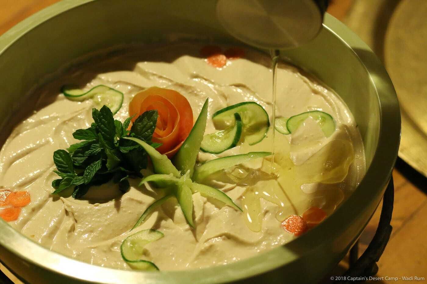 En skål cremet suppe med agurkeskiver og gulerodspynt.