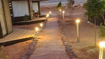 Un sendero que conduce a un edificio de fachada de piedra y una serie de luces a lo largo del camino.